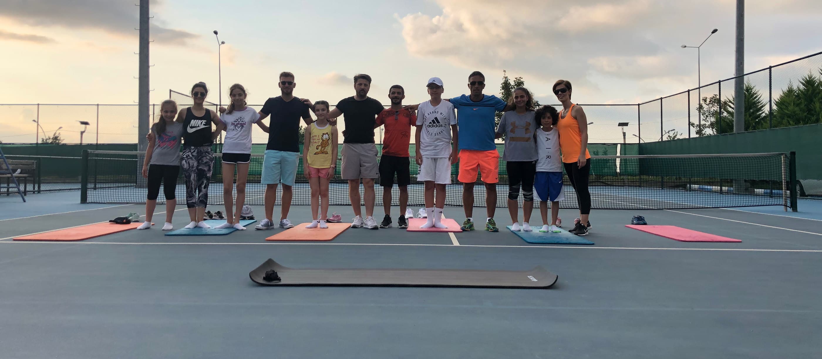 Akşam ışığında kortta sıraya dizilip ısınma çalışması yapan sporcular